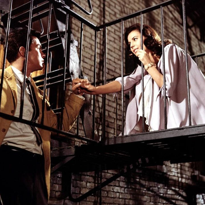 A man and woman look at each other on a fire escape.
