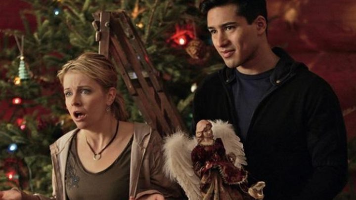 Melissa Joan Hart and Mario Lopez by a Christmas tree in Holiday in Handcuffs.
