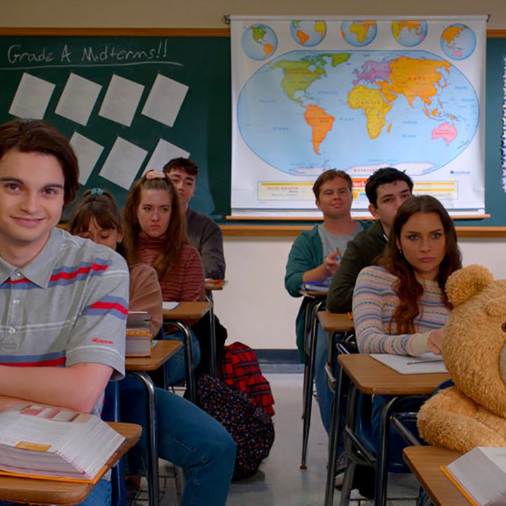 John and Ted sitting next to one another in a classroom from the Peacock prequel series Ted.