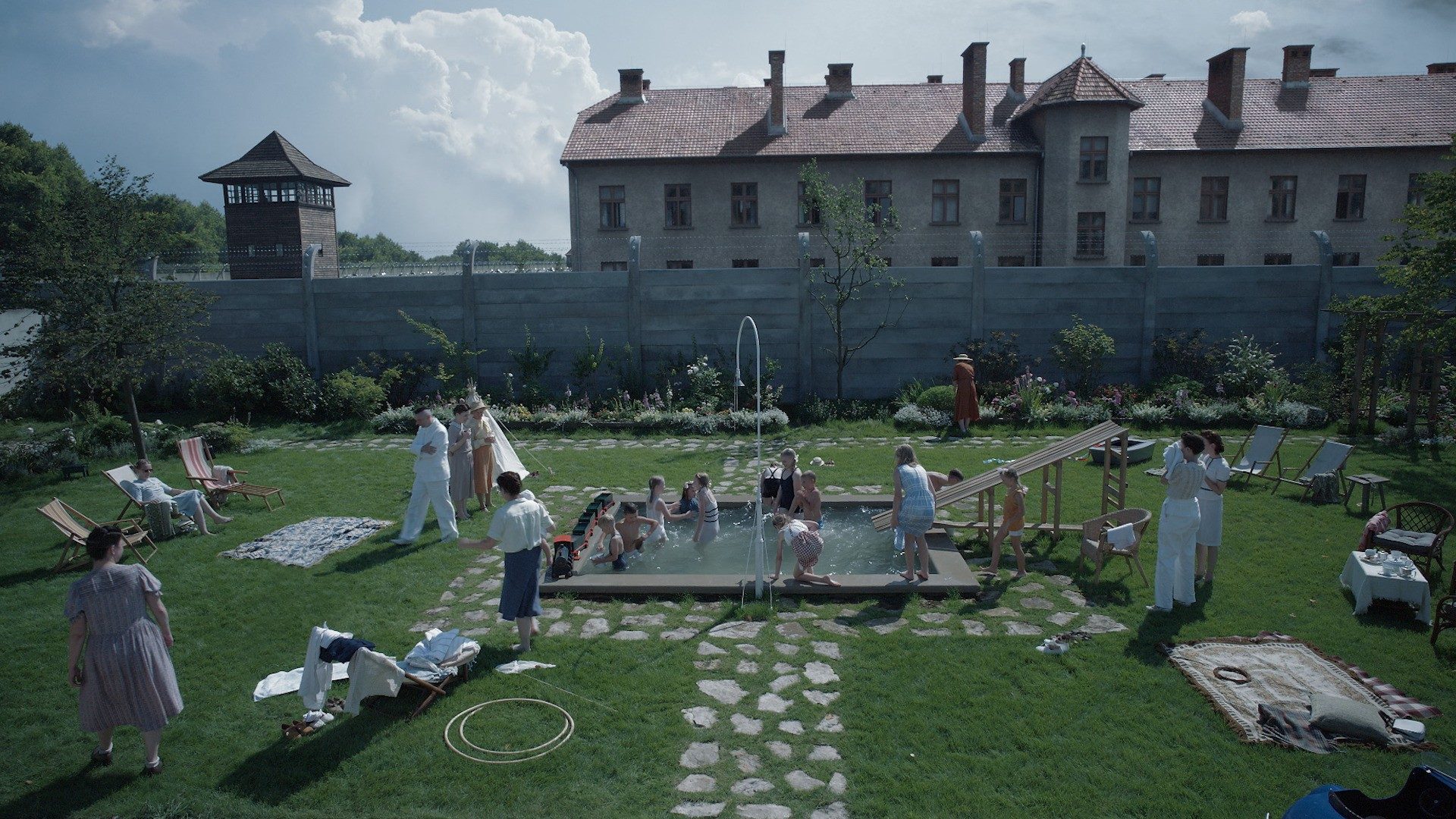 A family in a yard with a pool in The Zone of Interest.