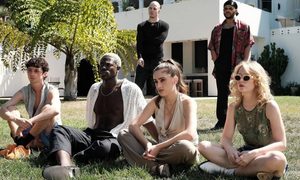 6 people sit and stand on a lawn in The Idol.