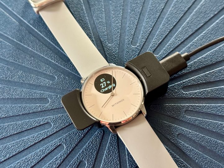 Withings ScanWatch Light charging in cradle.