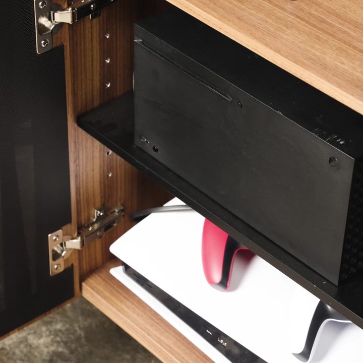 Xbox Series X and a PS5 on the shelves of a media cabinet.