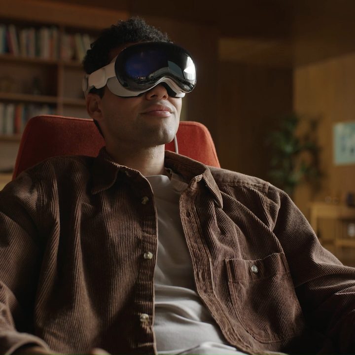 A person wears an Apple Vision Pro in a dim room.