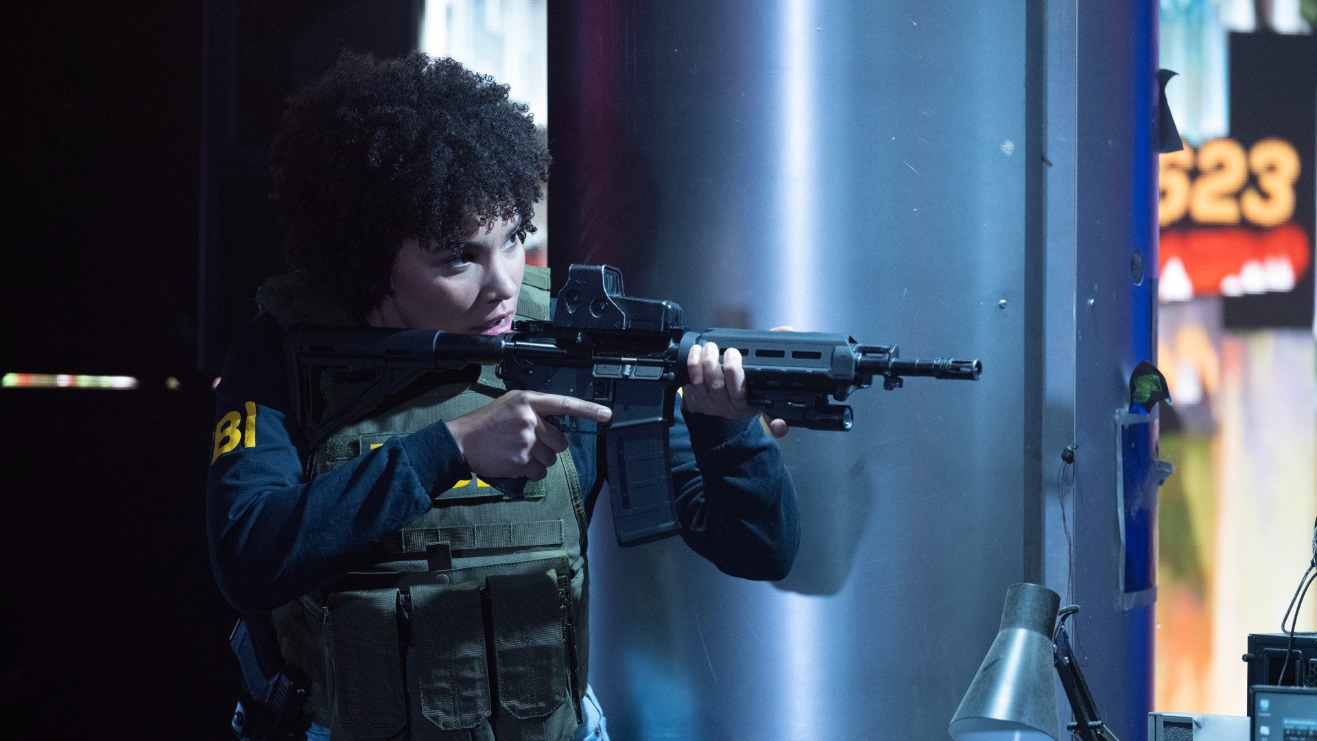 Emmy Raver-Lampman aims a rifle in a still from The Beekeeper