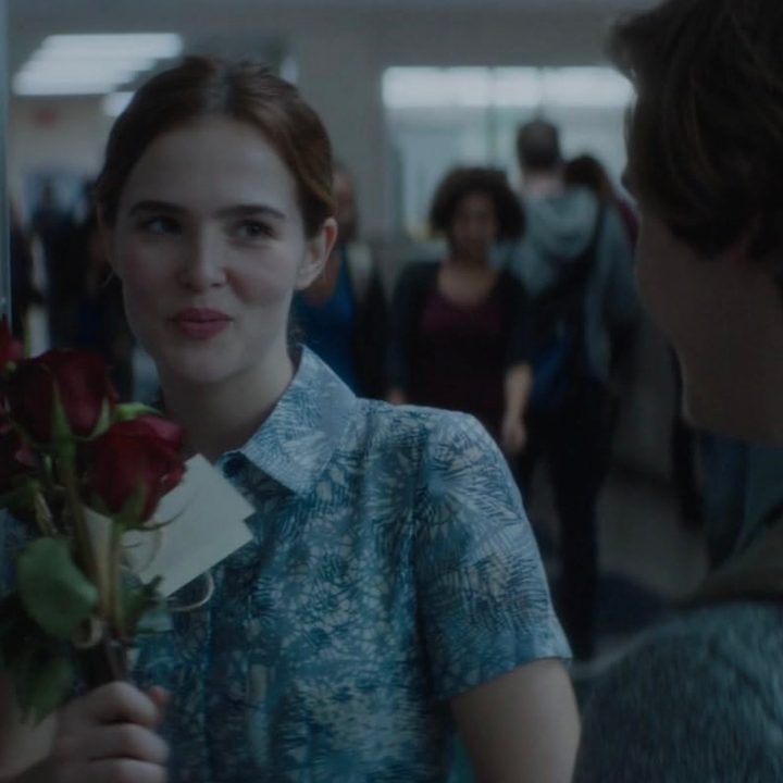 Zoe Deutch holds a rose and stares at a boy.