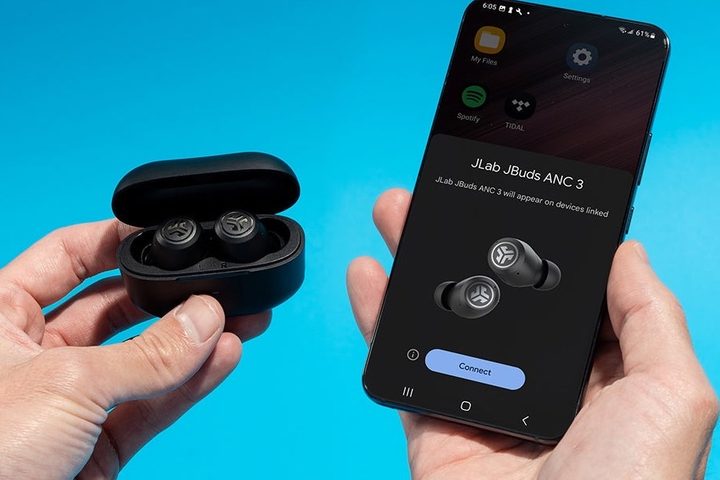 JLab JBuds ANC V3 seen next to smartphone.