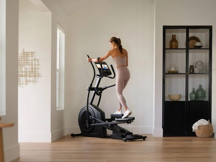 A woman works out in her home on the NordicTrack AirGlide elliptical.