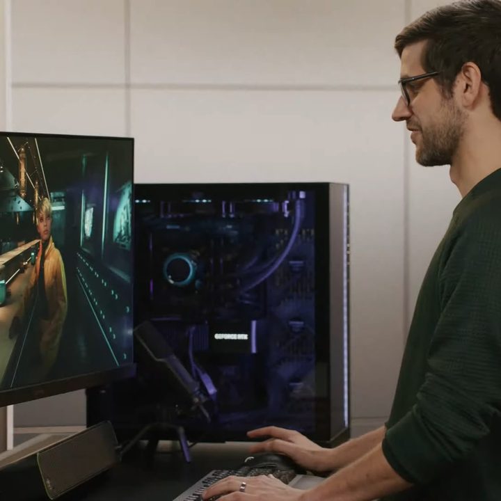 A man stands in front of a gaming PC.