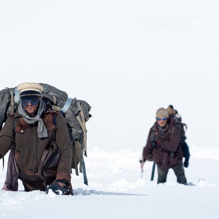 Two survivors trek through the heavy snow in a still from Society of the Snow
