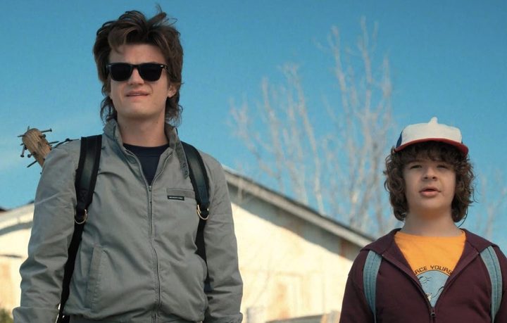 Steve and Dustin stand next to each other and stare in Stranger Things.