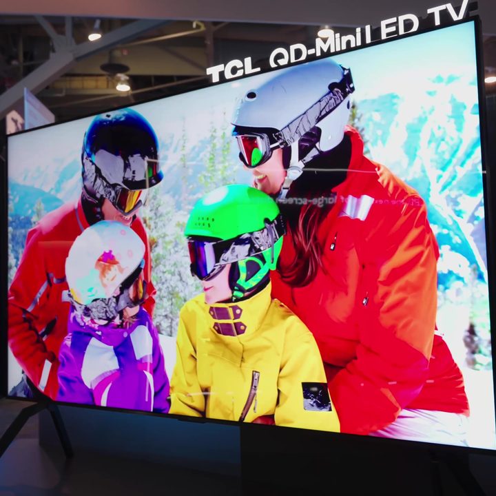 A family of skiers in brightly-colored gear shown on a TCL 115-inch TV.