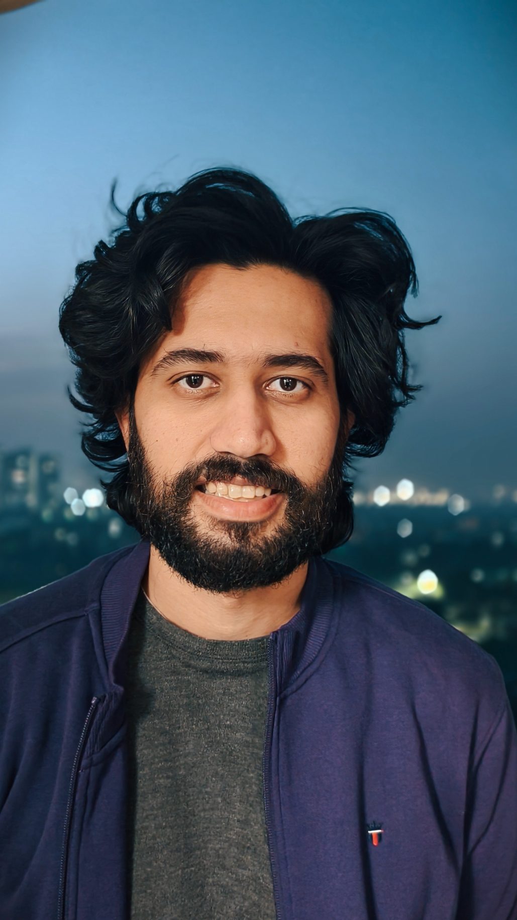 Picture of man wearing purple jacket and gray t-shirt taken with the Vivo X100's Zeiss camera.