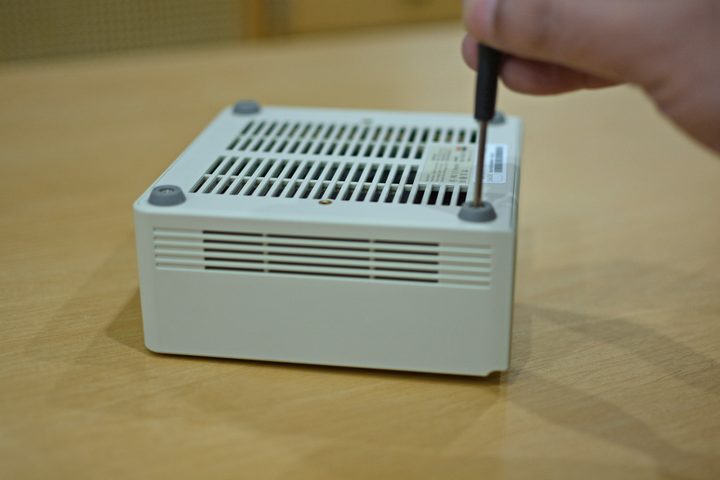 A screwdriver being used to open the bottom screws of the Ayaneo Retro Mini PC AM01.