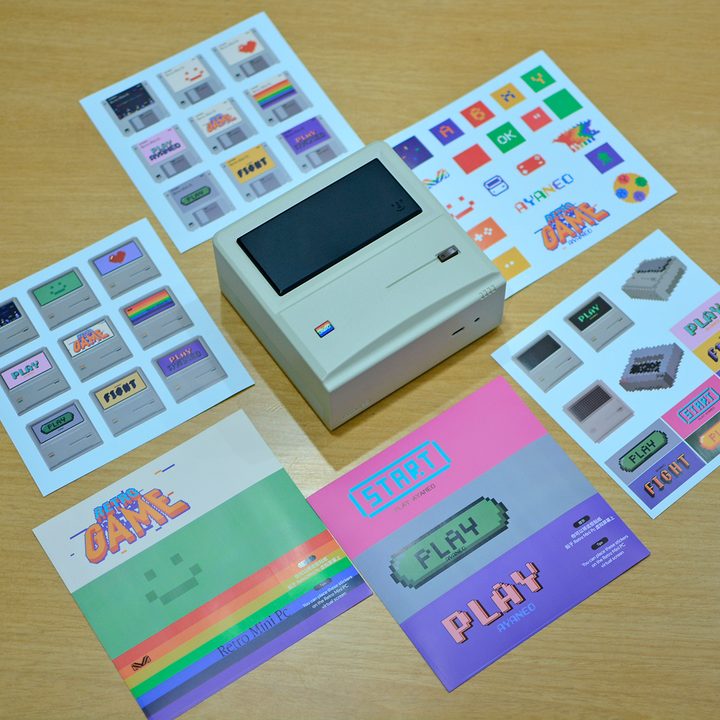 The Ayaneo Retro Mini PC AM01 with all the bundled stickers placed on a desk.