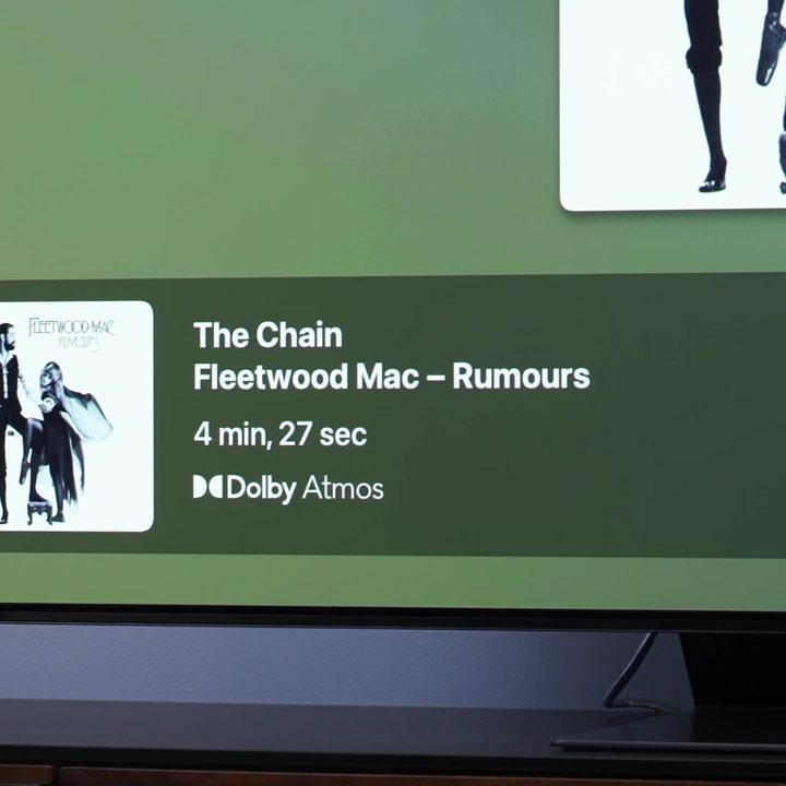 An information chyron showing a song title and album information shown on the bottle left of a TV.