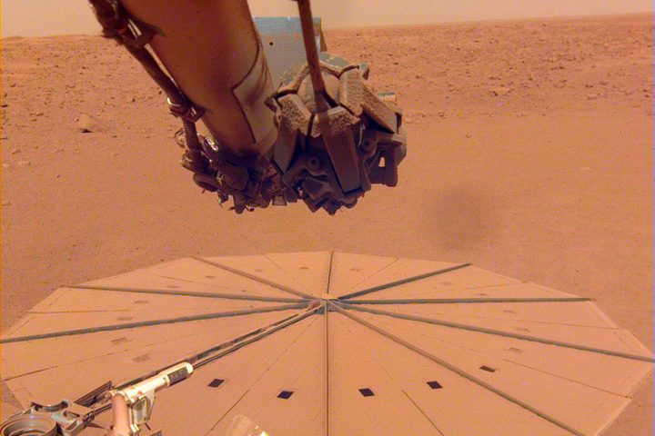 The InSight Mars rover's solar panels are shown covered in dust.