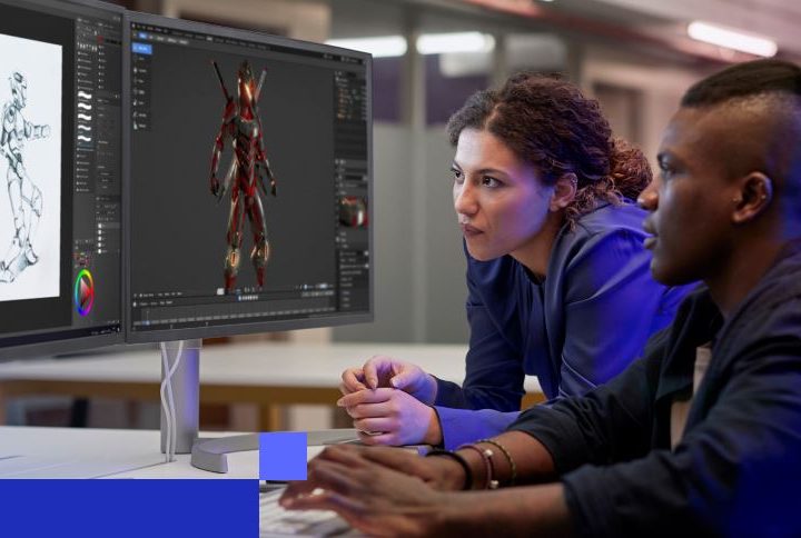 A woman and a man sit together by a desk, using a graphics editing program on a computer.