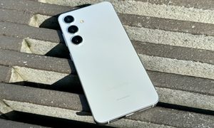 Samsung Galaxy S24 in Marble Gray laying on a wooden planter.