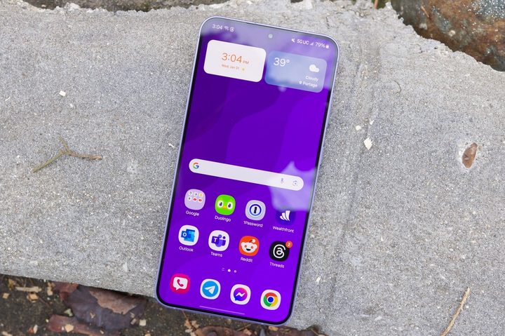 The Samsung Galaxy S24 Plus resting on a concrete slab, with the screen turned on and showing the home screen.