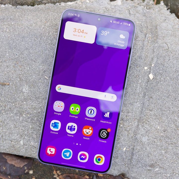 The Samsung Galaxy S24 Plus resting on a concrete slab, with the screen turned on and showing the home screen.
