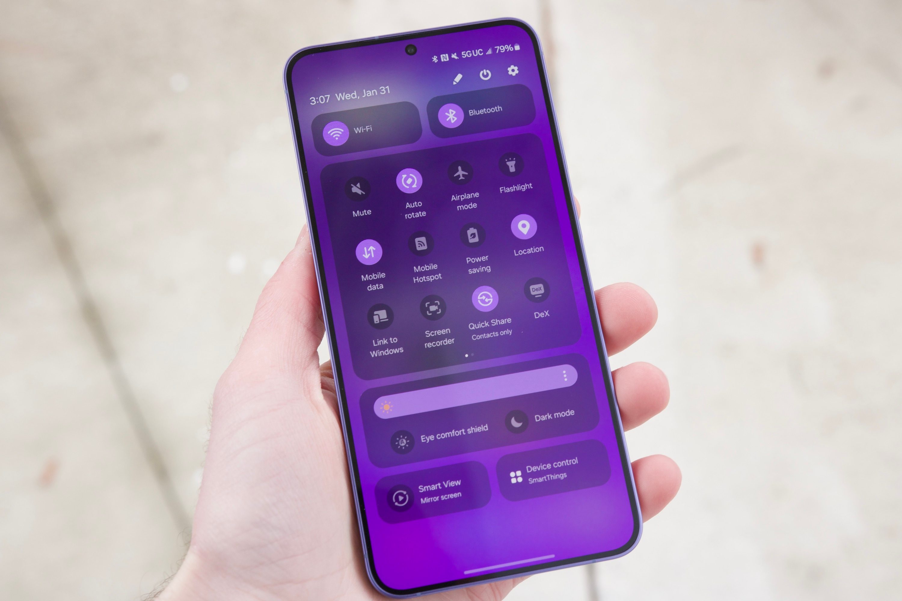 Someone holding the Samsung Galaxy S24 Plus. The screen is on and showing the phone's Quick Settings.