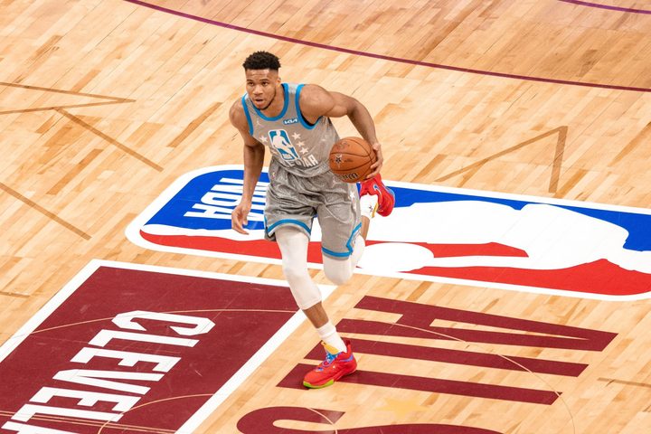 Giannis Antetokounmpo dribbles down a basketball court.