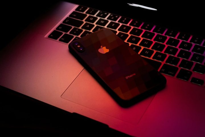 A MacBook and iPhone in dark red light.