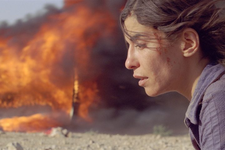 Mélissa Désormeaux-Poulin in front of something burning in the background in Incendies (2010).