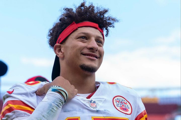 Patrick Mahomes of the Kansas City Chiefs holds his shoulder pads and smiles.
