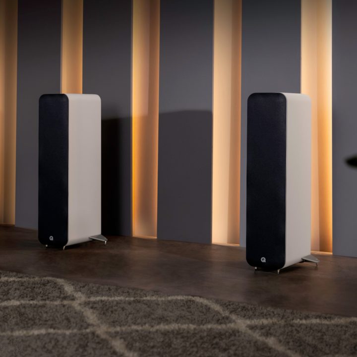 Two white Q Acoustics M40 powered micro-tower wireless audio system speakers.