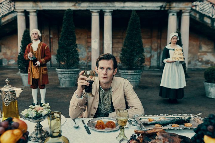 Simon Bennebjerg holds a glass of wine in The Promised Land.