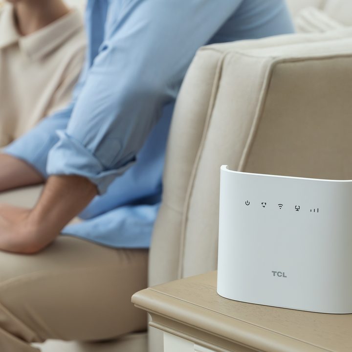 TCL Linkhub HH132 Pro on living room table beside two people sitting on a couch in the background.