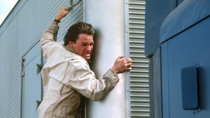 A man holds on to the side of a truck in Breakdown.