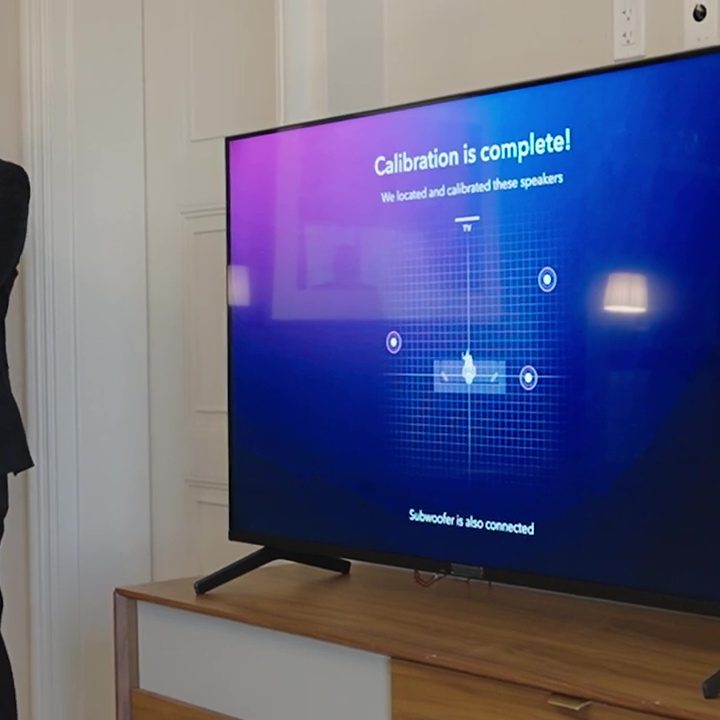A man stands next to a TV that shows calibration is complete for Dolby Atmos FlexConnect at CES 2024.
