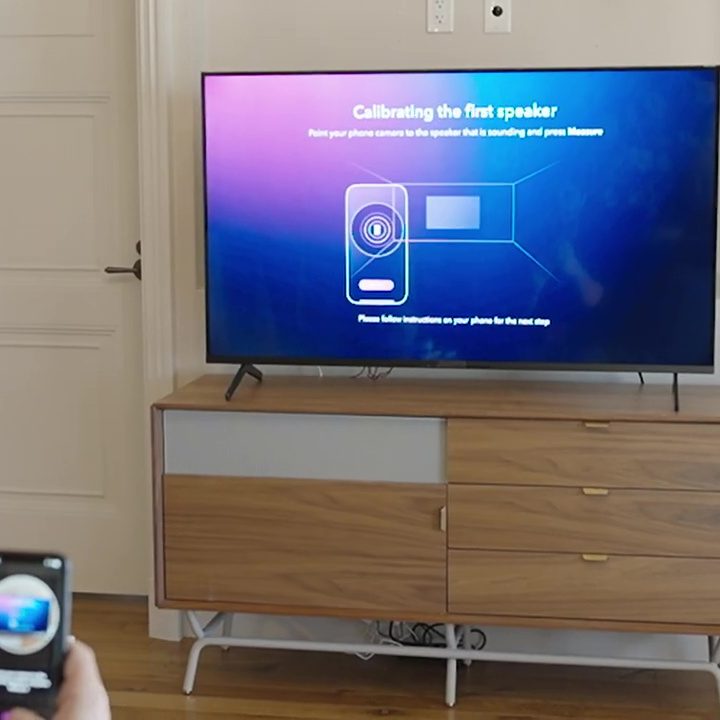 A man uses an an app to calibrate a Dolby Atmos FlexConnect.