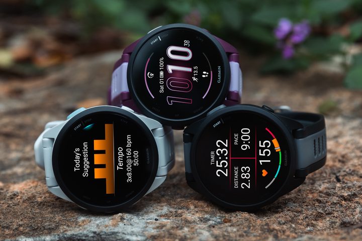Three Forerunner 165 watches stacked on a forest floor.