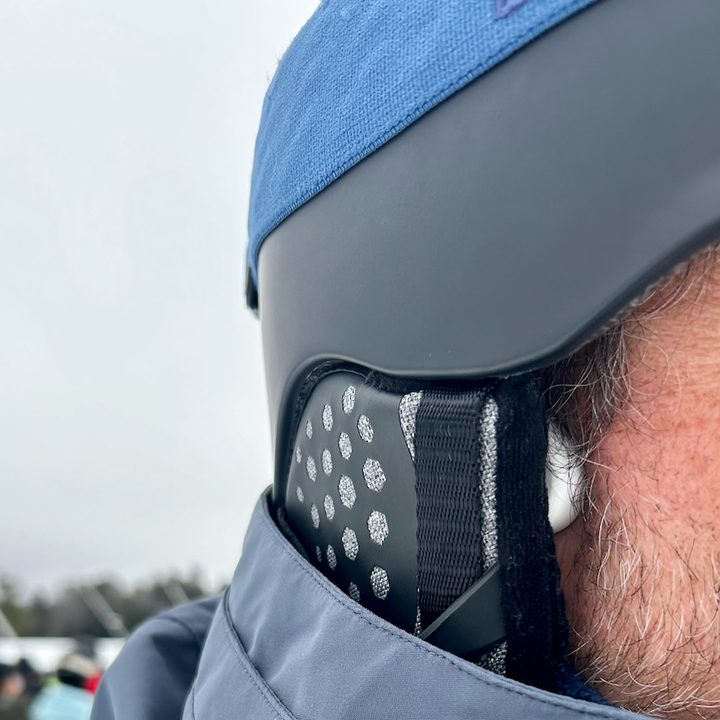 The H2O SnowPro skiing headphones peeking out from under a ski helmet.