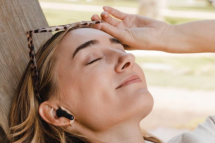 A woman wearing a pair of the JBL Tune Flex earbuds in black.