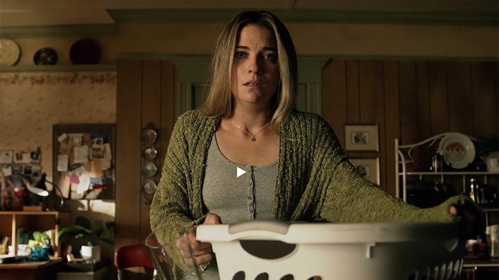 Allison from Kevin Can F**k Himself holding a bin of laundry and looking upset.