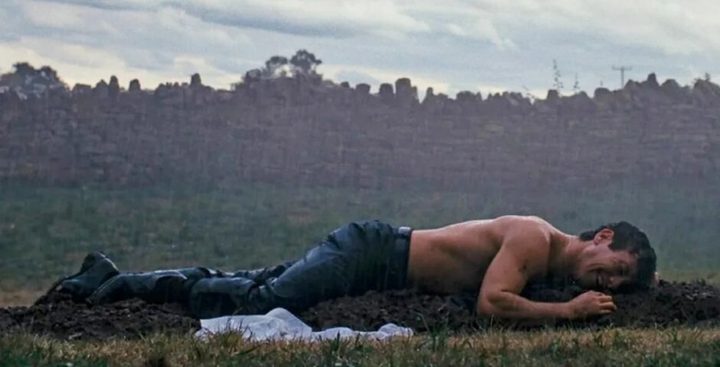 A man lays crying on a grave in Saltburn.