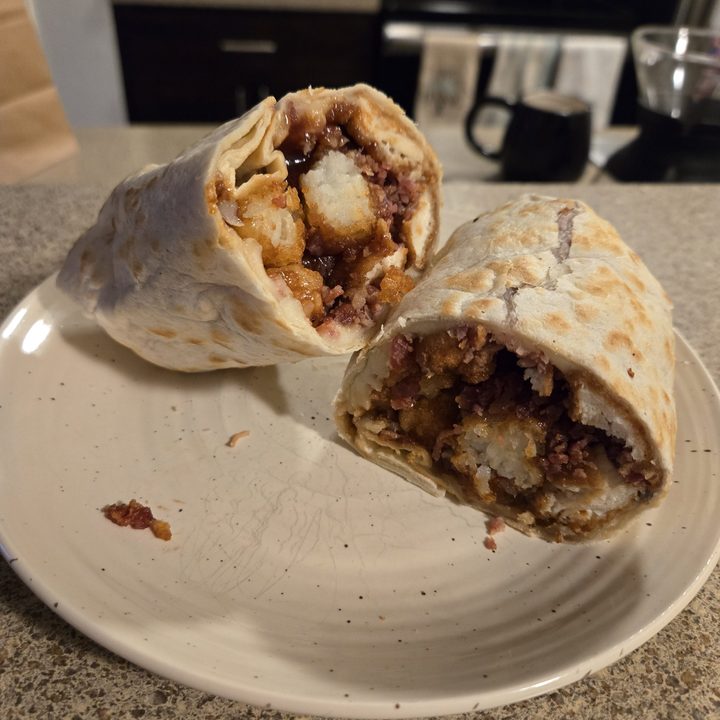 A photo of a wrap with tater tots and chicken tenders.