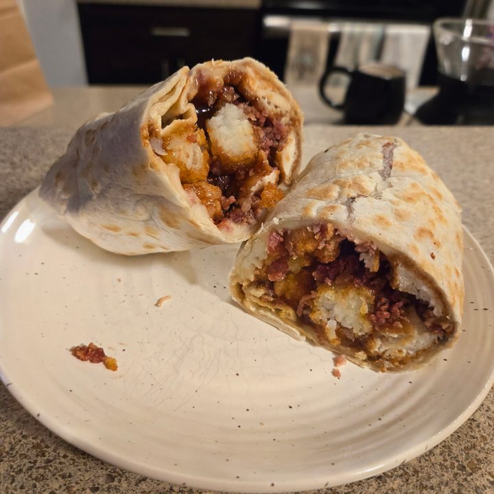 A photo of a wrap with tater tots and chicken tenders.