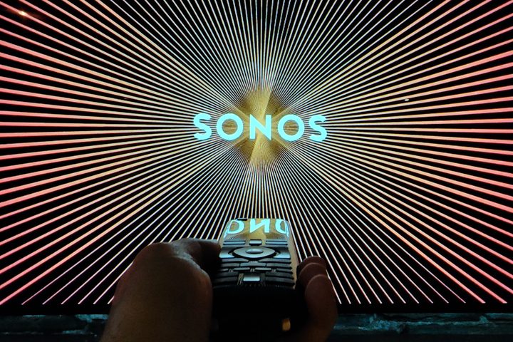 A remote contol pointed at a TV displaying the Sonos logo.