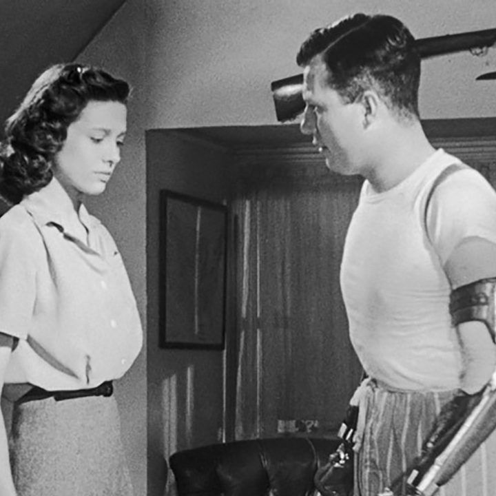 A black and white image of Harold Russell standing beside a woman in a scene from The Best Years of Our Lives.