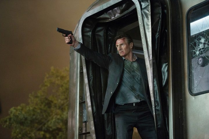 A man aims his gun on a train in The Commuter.