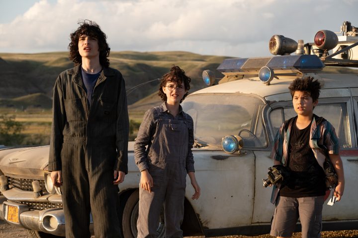 Trevor, Phoebe, and Podcast stand by the Ecto-1 in Ghostbusters: Afterlife.