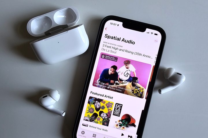 Apple Music's spatial audio collection seen on an iPhone 14, next to Apple AirPods Pro.