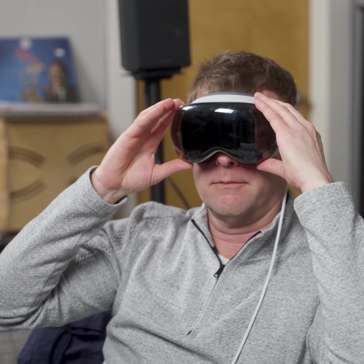 A man adjusts an Apple Vision Pro headset over his eyes.