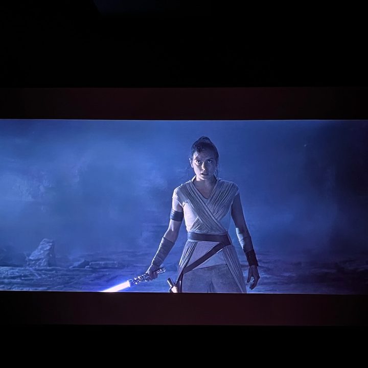 A scene from Star Wars:The Rise of Skywalker with Rey holding a lightsaber.